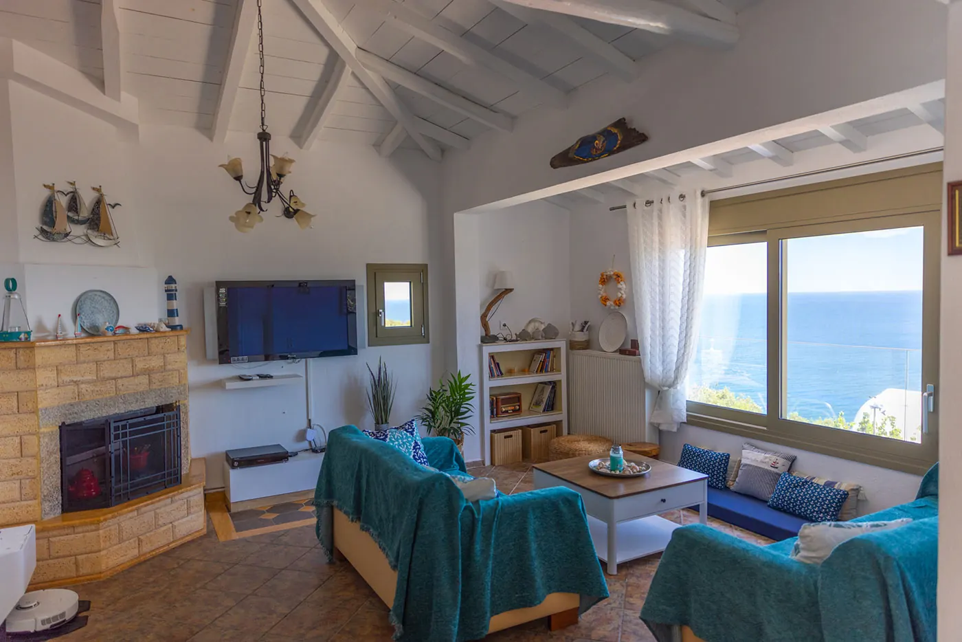 Living room under a white wooden ceiling, with a fireplace and sea views