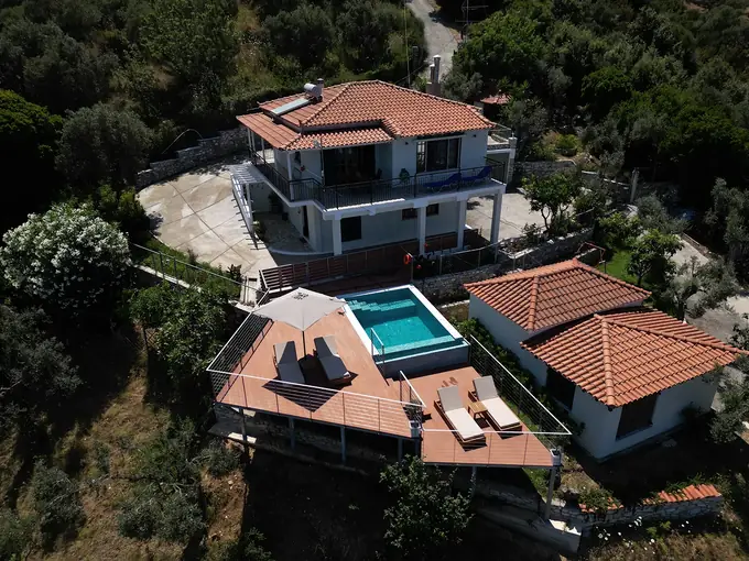 Aerial view of the villa, its pool deck and the green hillside