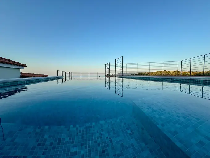 The infinity edge of the pool meeting the sea at dusk