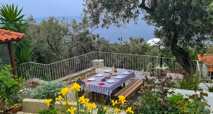 A garden table set among flowers above the sea