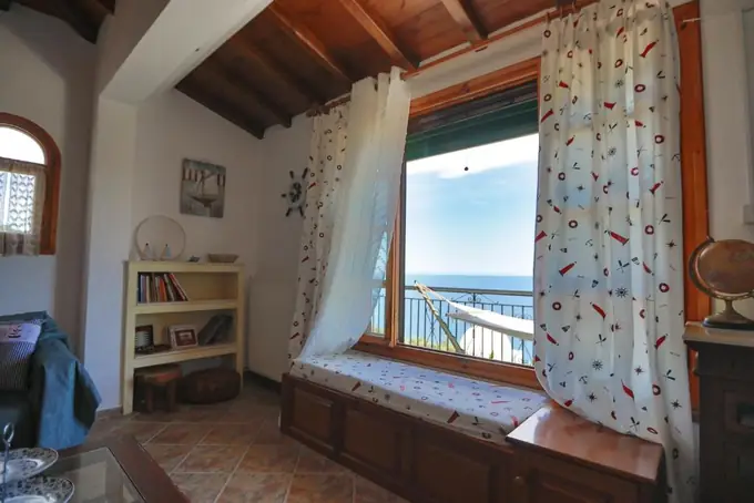A room with a window seat and sea views under a wooden ceiling