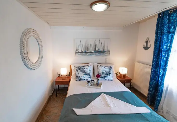 Double bedroom with a sailboat painting and blue curtains