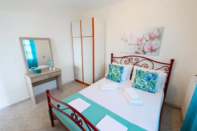Bedroom with a red iron bed and tropical-print cushions