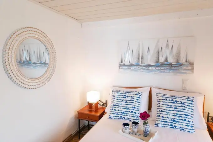 Bed with blue-and-white cushions under a sailboat painting