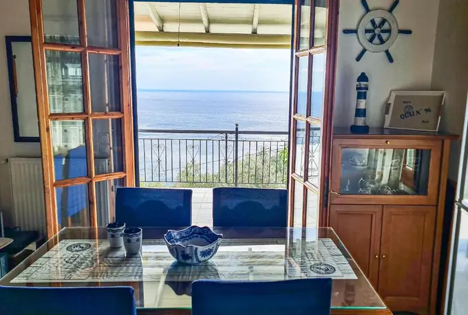 Dining table with blue chairs in front of the sea view